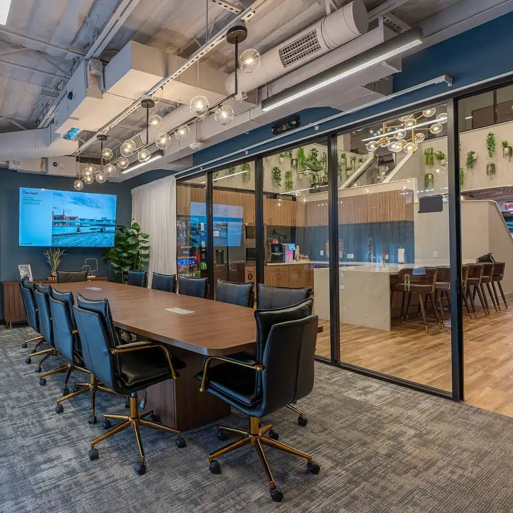 Conference room with large table and 12 chairs and wall-mounted television in coworking space in Texas Conference room with large table and 12 chairs and wall-mounted television in coworking space in Texas