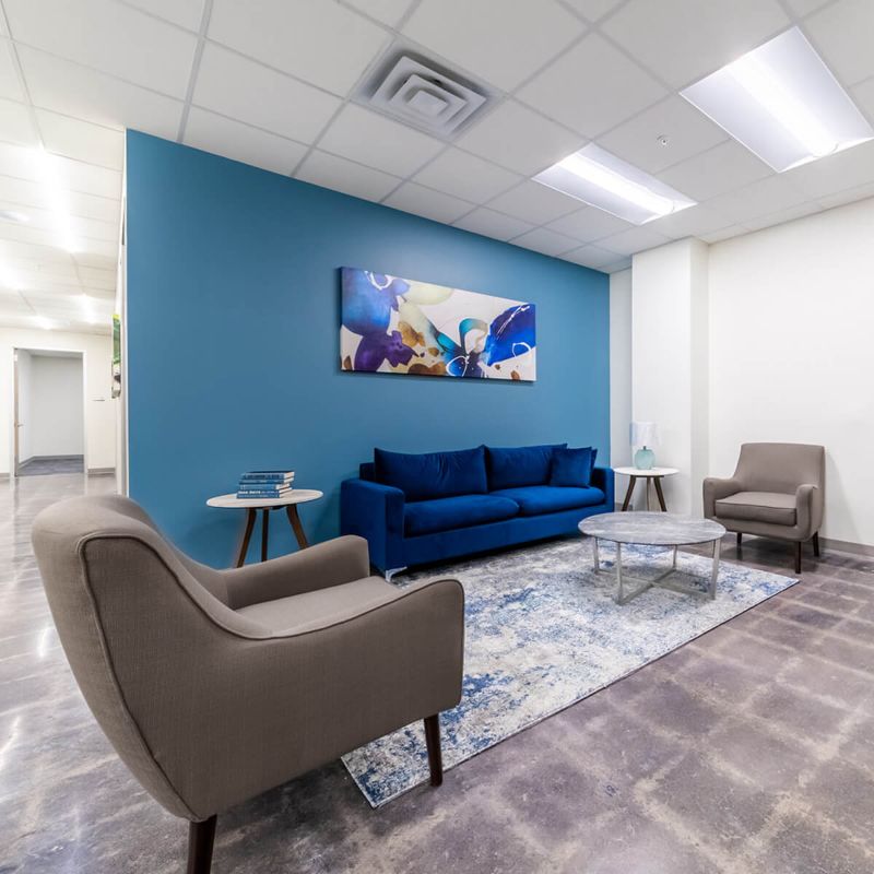 couch and chairs in lobby with blue wall and painting in office from Urban Office